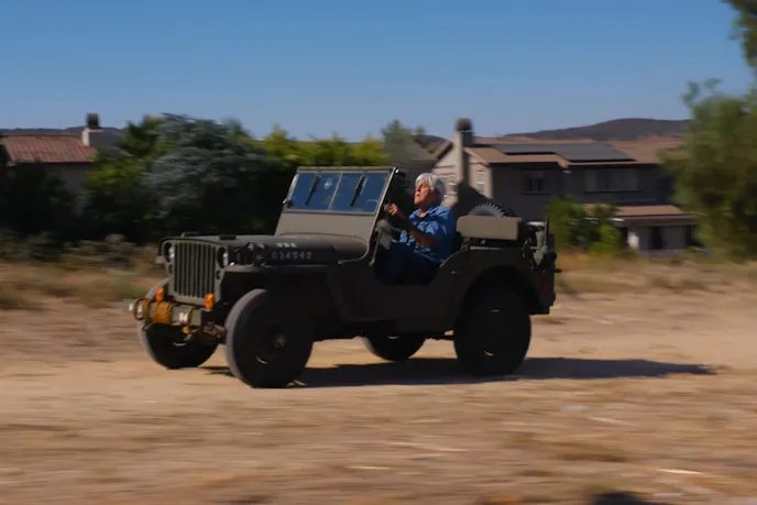 Jey Leno driving his 1942 Ford Jeep on an off-road pavement